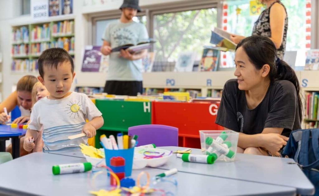 Teacher and child sitting at a table in a kindergarten classroom